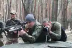 Präzise Schießübung im Wald mit Militärpersonal, Fokus auf Zielgenauigkeit und taktisches Training, in einer natürlichen Umgebung mit Bäumen und Herbstlaub.