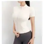 Moderner Damen-Workout-Top in Creme mit Reißverschluss, ideal für Sport und Freizeit, aus atmungsaktiven Materialien für optimalen Komfort und Style.