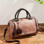 Lederhandtasche in rosé mit schwarzen Griffen und eleganten Metallakzenten, ideal für stilbewusste Frauen.