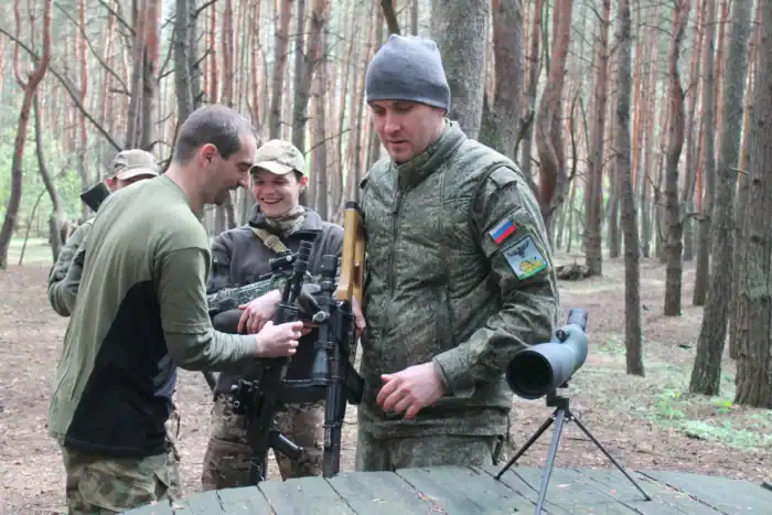 Praktische Waffentest in einem Wald mit Soldaten, Fokus auf militärische Ausrüstung und Outdoor-Aktivitäten.