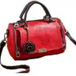 Rote Lederhandtasche mit vielen Reißverschlüssen und dekorativem Rosen-Anhänger, stilvoll und elegant, ideal für Damenmode und Accessoires.